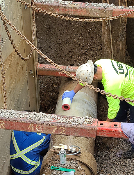 A USI expert technician is applying fiberglass wrap to the pipe to prepare for coating.